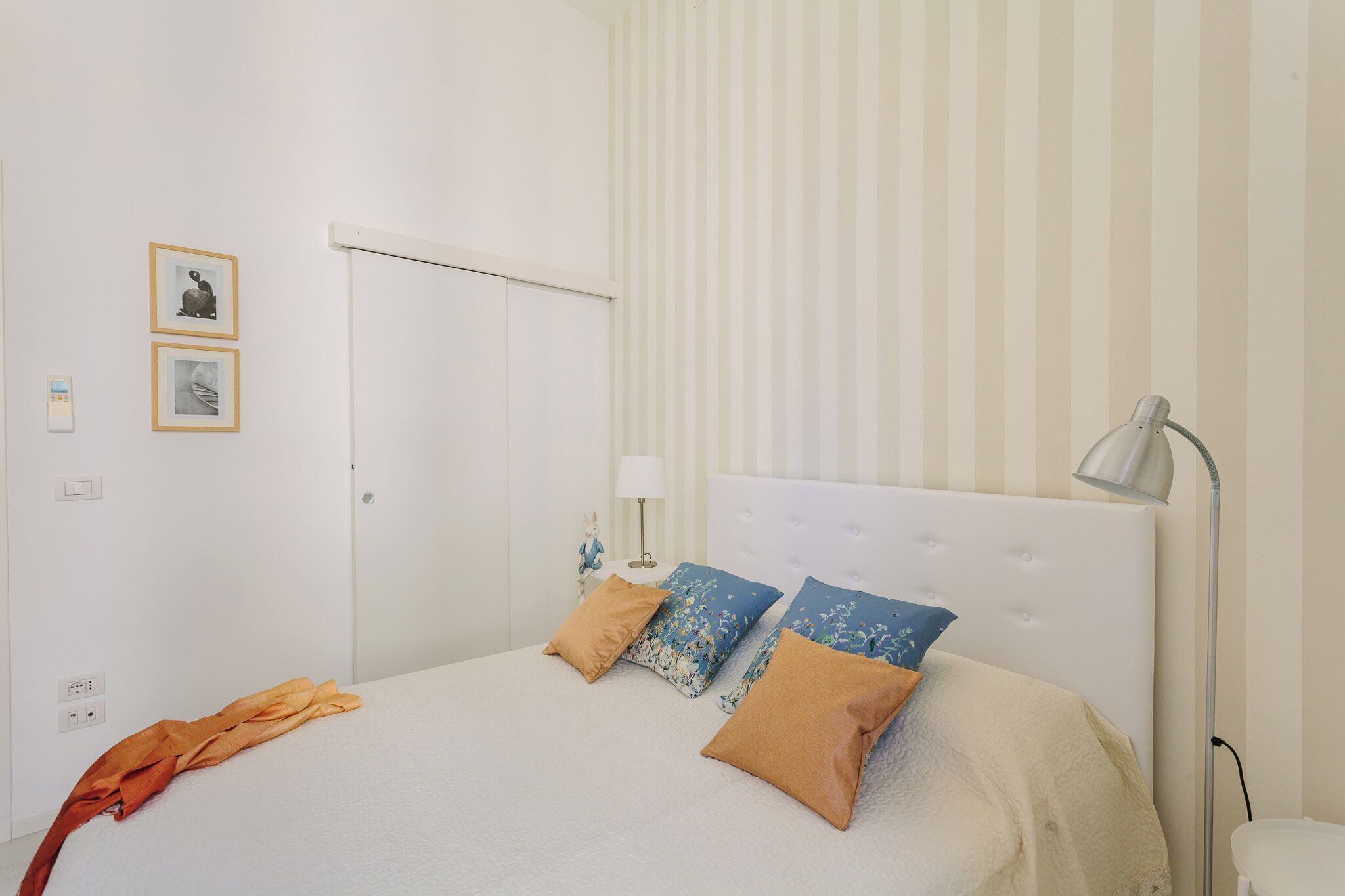Une chambre à coucher avec un lit, des oreillers, une lampe et une porte.