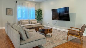 Un salon comprenant un canapé, une table basse, un fauteuil, un téléviseur et une plante.