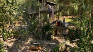 Une cabane rustique avec des fondations en pierre, une terrasse en bois et un petit porche.
