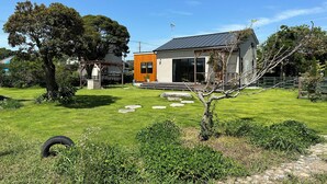 A modern house with a large lawn, a wooden deck, and a stone pathway. - Aiming to create a place where even timid dogs can play to their heart's content. (九十九里町)