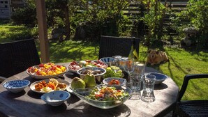 A round wooden table set outdoors with various dishes, glasses, and a bottle. - Aiming to create a place where even timid dogs can play to their heart's content. (九十九里町)
