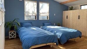 A bedroom with two beds, wooden flooring, a wardrobe, and a potted plant. - Aiming to create a place where even timid dogs can play to their heart's content. (九十九里町)