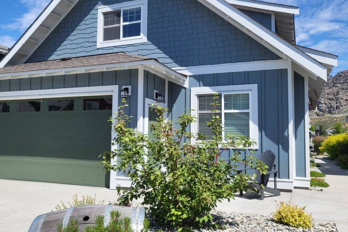 Une maison à deux étages avec un garage, une véranda et un petit jardin.