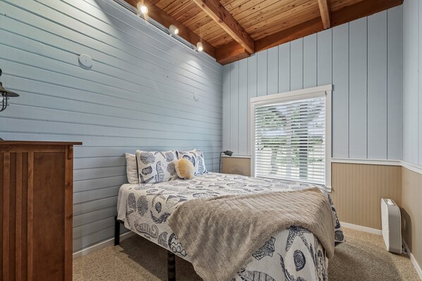 Un dormitorio con una cama, un aparador de madera, un radiador y una ventana con persianas.