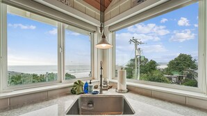 Una cocina con un ventanal grande, un lavabo y una lámpara colgante.