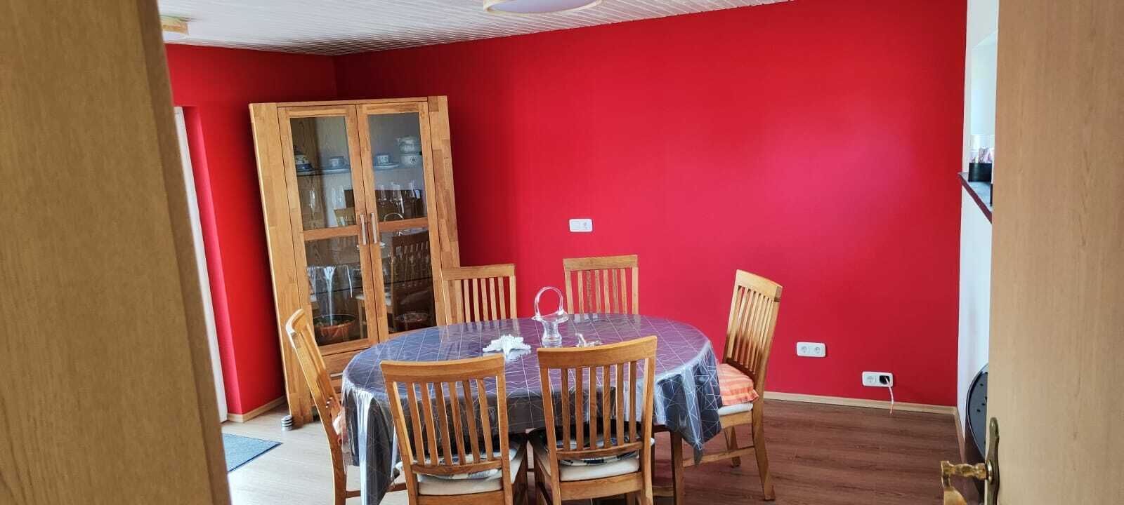Un coin repas avec une table ronde, des chaises en bois et un buffet aux portes vitrées.