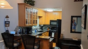 A modern kitchen with wooden cabinets, a central island, and a dining area with chairs.