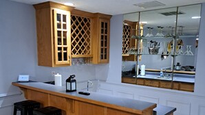 A kitchen with a wooden bar and stools, a refrigerator, and a sink.