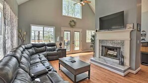 A spacious living room with a large leather sectional sofa, a fireplace, and a television mounted above it.