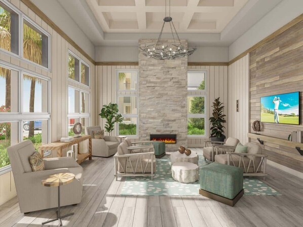 A spacious living room with a fireplace, comfortable seating, large windows, and a TV on the wall.
