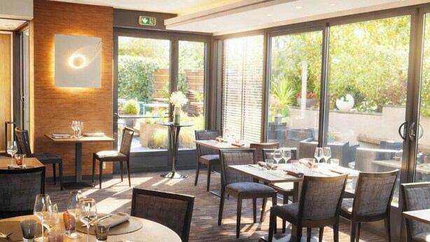 A restaurant with outdoor seating, large windows, and a modern interior design.