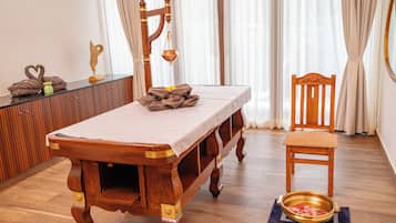Relax with a soothing massage on a traditional table, accompanied by a comfortable chair.