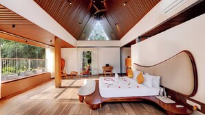 A modern bedroom with a wooden ceiling, a large bed with white bedding, and a view of greenery outside. - Sandesh Water Edge Kabini  (Heggadadevankote)