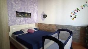 A bedroom with a bed, a small chair, a wall-mounted light, and a decorative butterfly wall decal.