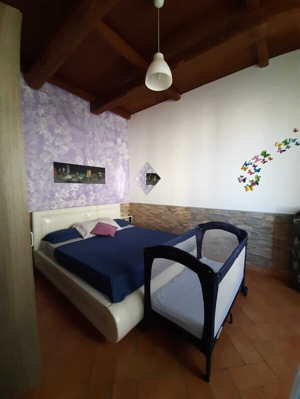 A bedroom with a bed, a small chair, a wall-mounted light, and a decorative butterfly wall decal.