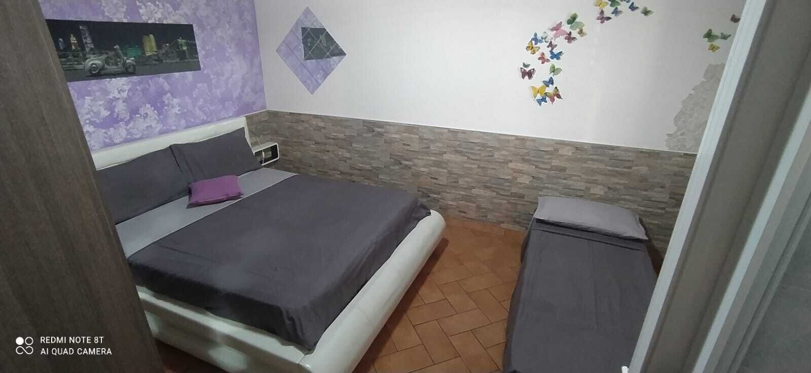 Una camera da letto con un letto, un comodino e una parete decorata con farfalle.
