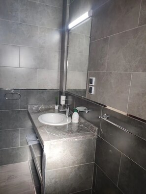 A modern bathroom with a marble sink, a mirror, and a towel rack. - Apartment in Tamraght with a terrace and breathtaking views of the sea and mountains (Tamraght oufella)