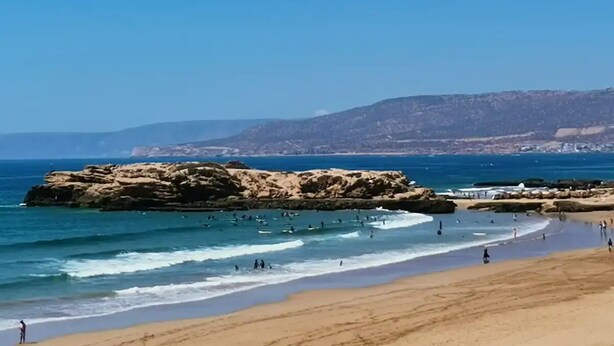 Une plage avec des formations rocheuses et une eau d’un bleu cristallin.