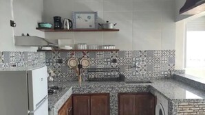 Une cuisine dotée d’un plan de travail en granit, de meubles en bois, d’un lave-linge encastré et de carreaux décoratifs sur le mur derrière l’évier.