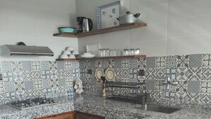 Une cuisine dotée de plans de travail en granit, de meubles en bois et de carreaux décoratifs sur le mur derrière l’évier.