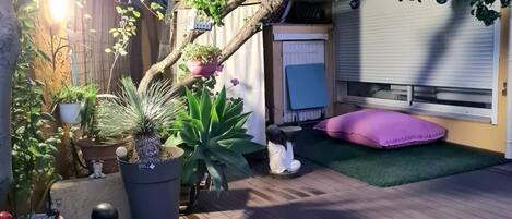 A wooden deck with potted plants, a statue, and a small garden area with artificial grass.