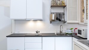 A modern kitchen with white cabinets, a black countertop, a built-in microwave, and a sink. - Banchi al Patio - Castel Sant Angelo (Rome)