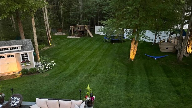 A well-maintained backyard with a lawn, a wooden deck, and a boat-shaped swing set. - Saratoga Racetrack and SPAC getaway  (Saratoga Springs)