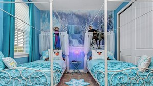 Un dormitorio con dos camas, un mural de un paisaje nevado y una mesita de noche con una lámpara.