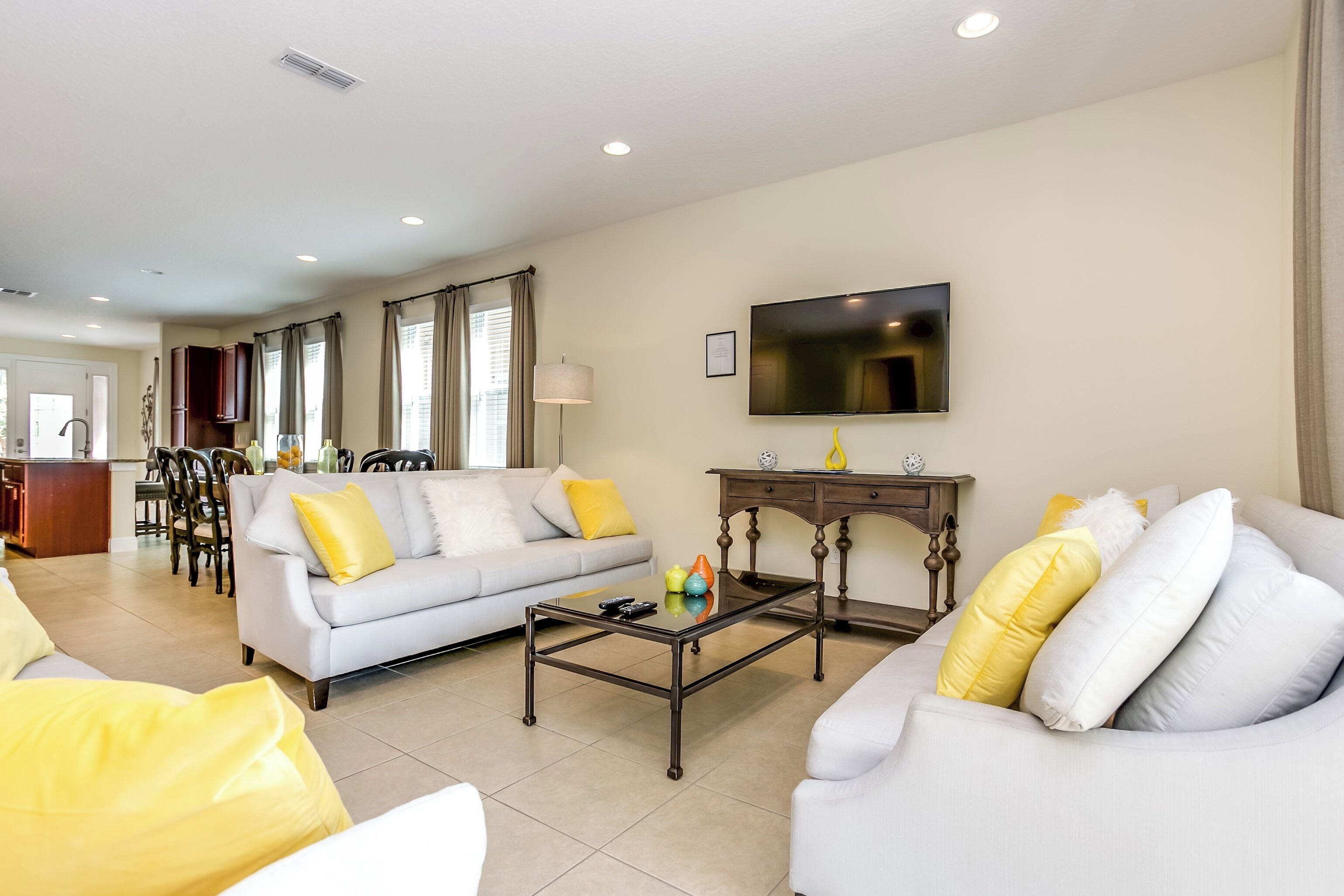 A living room with a sofa, a coffee table, and a TV mounted on the wall.