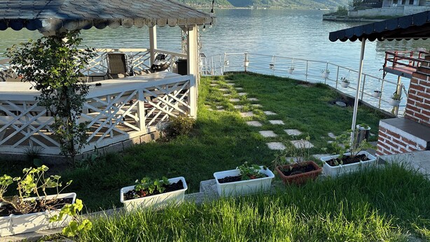 A lakeside patio with a gazebo, outdoor seating, and potted plants. - NOAH river house (Orsova)