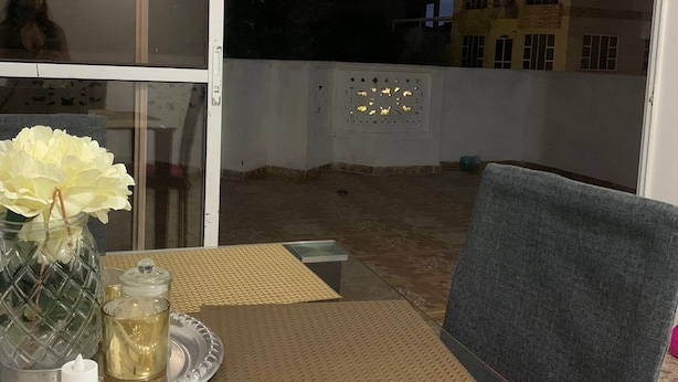 An indoor balcony with a table set for dining, a chair, and a decorative vase with flowers. - Hostel VIM (Cartagena)