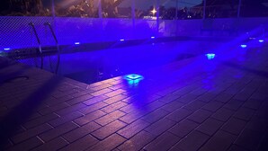 A swimming pool with blue lighting, surrounded by a white fence and a brick deck. - Relaxing pet-friendly house with a heated pool near Beaches, Golf & Dining! (Port Charlotte)