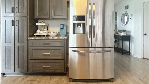 A kitchen with dark wooden cabinets, a stainless steel refrigerator, a coffee maker, and a water dispenser. - Relaxing pet-friendly house with a heated pool near Beaches, Golf & Dining! (Port Charlotte)