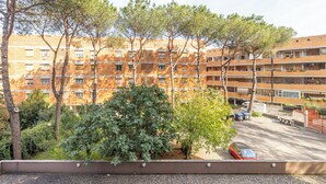 Un edificio de varios pisos con fachada de ladrillo, rodeado de árboles y vegetación.