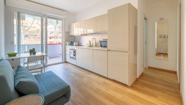 Un apartamento moderno con cocina, comedor y balcón con vistas a edificios.