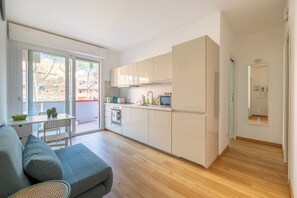 Eine moderne Wohnung mit Küche, Essbereich und einem Balkon mit Blick auf Gebäude.
