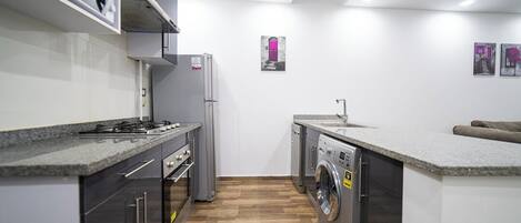 Uma cozinha compacta com forno embutido, micro-ondas e máquina de lavar roupa, pia e um pequeno espaço para sentar.