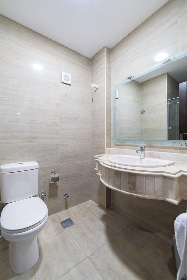 Une salle de bain avec des toilettes, un lavabo et une douche.