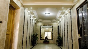 A hallway with marble walls, a large mirror, and potted plants. - Violet 133 (New Cairo)