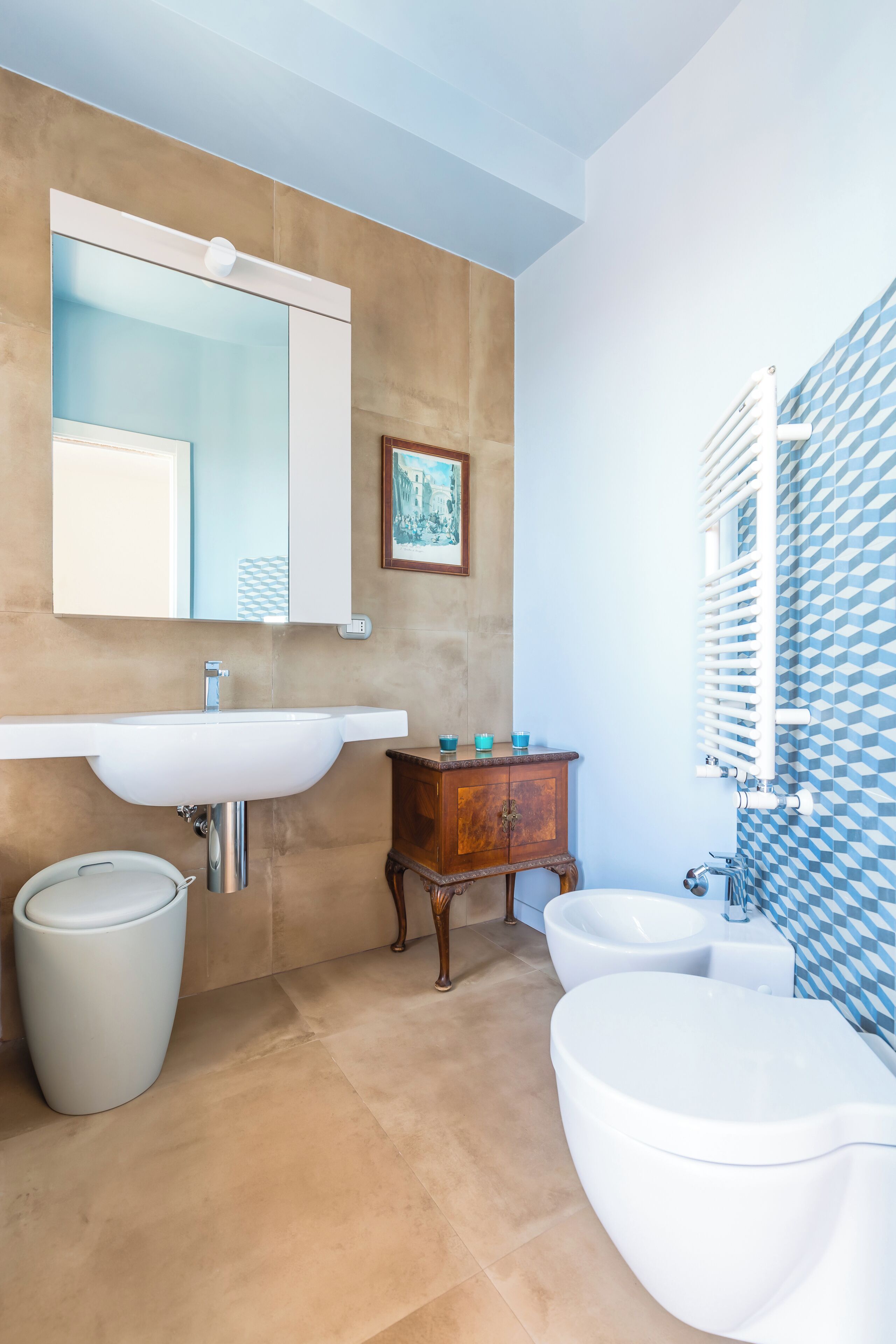 A bathroom with a white sink, a wooden cabinet, a bidet, and a toilet.