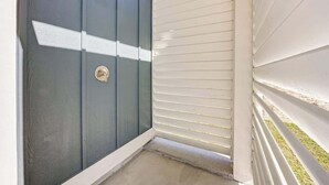 Een hoek van een gebouw met een donkerblauwe deur en wit beklede gevel.