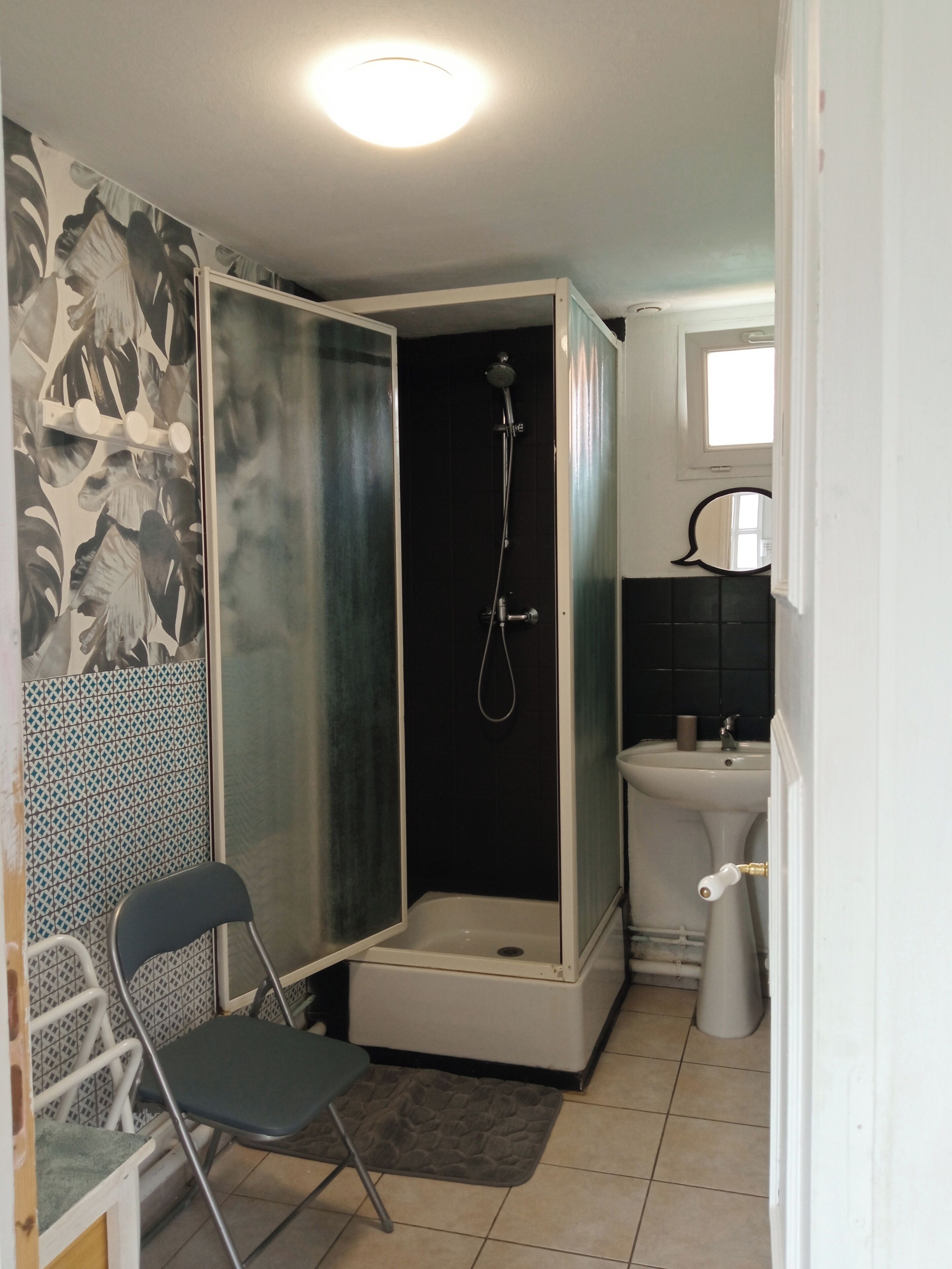 Une salle de bain avec une douche, un lavabo et une chaise.