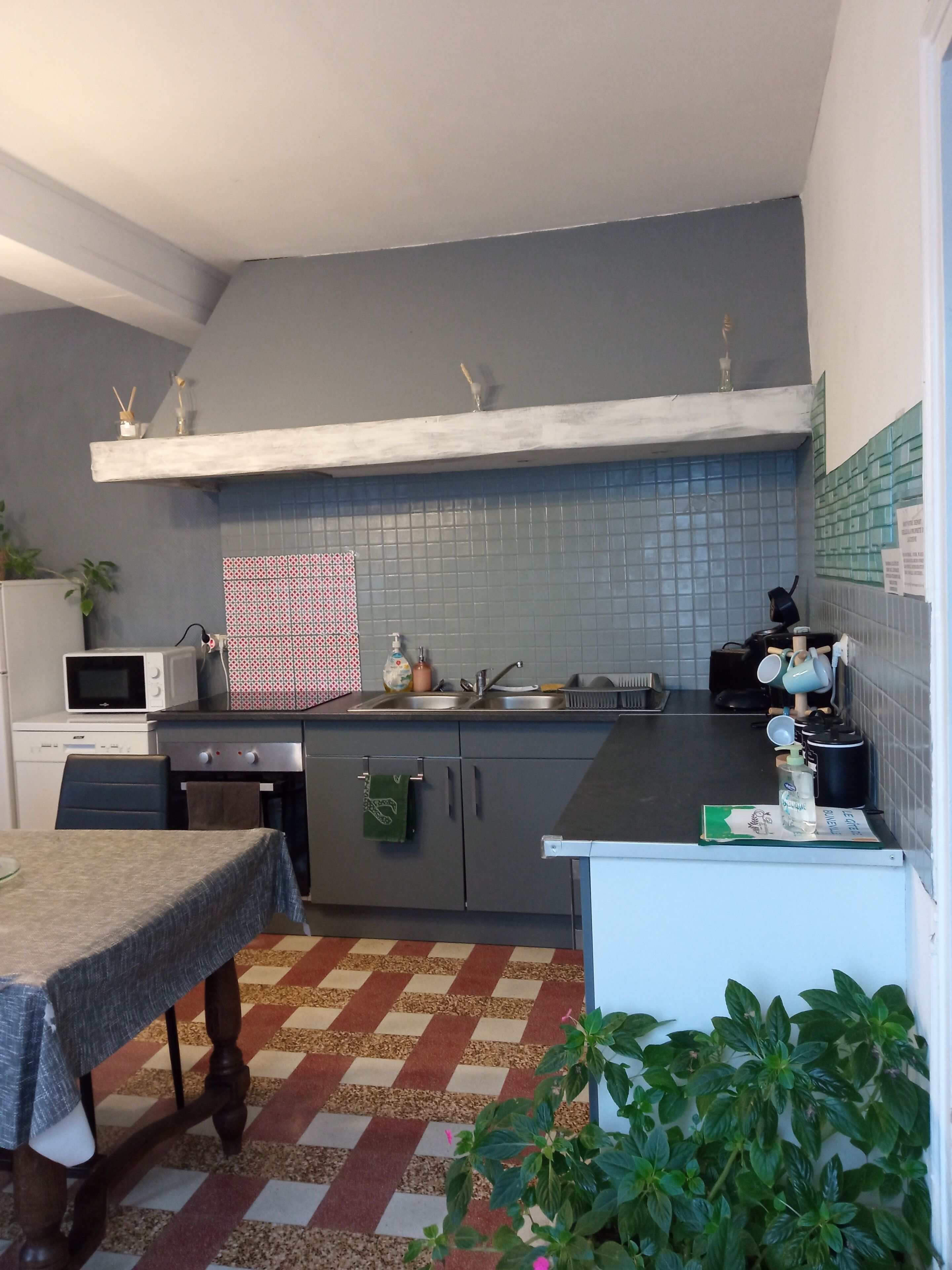 A compact kitchen with a microwave, stove, sink, and a small dining table.