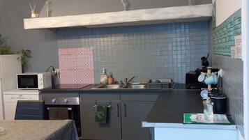A compact kitchen with a microwave, stove, sink, and a small dining table.