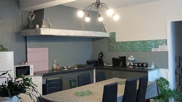 Een moderne keuken met een centraal eiland, eettafel, stoelen en diverse apparaten.