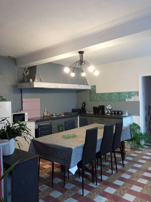 Una cocina moderna con una isla central, mesa de comedor, sillas y varios electrodomésticos.