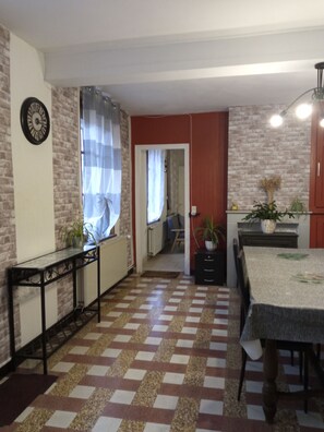 Una cocina con piso a cuadros, una mesa de comedor y un ventanal con cortinas.
