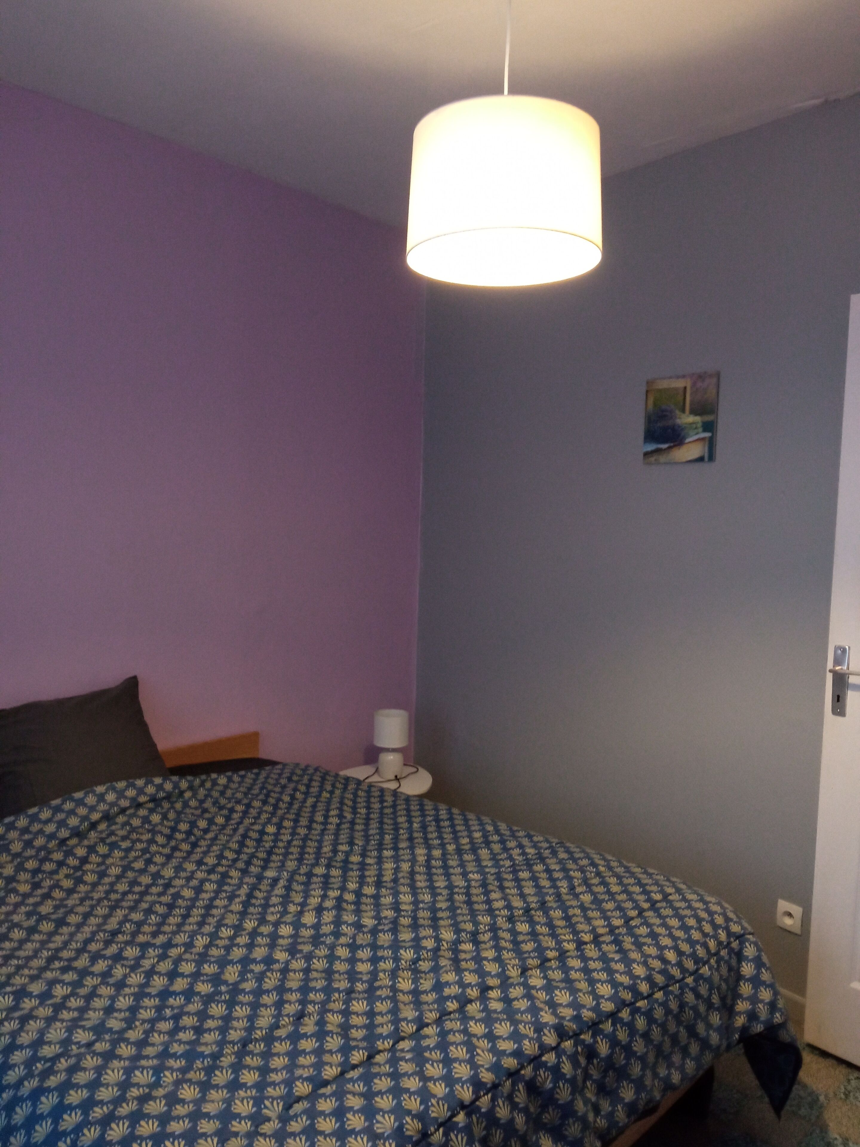 Ein Schlafzimmer mit Bett, Nachttischlampe und einer Tür.