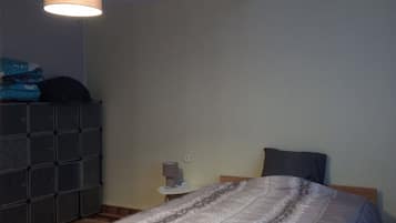 A bedroom with a bed, a dresser, a nightstand, and a hanging lamp.