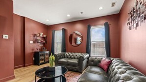 Un salon avec un canapé marron foncé, une table basse ronde et un meuble décoratif.